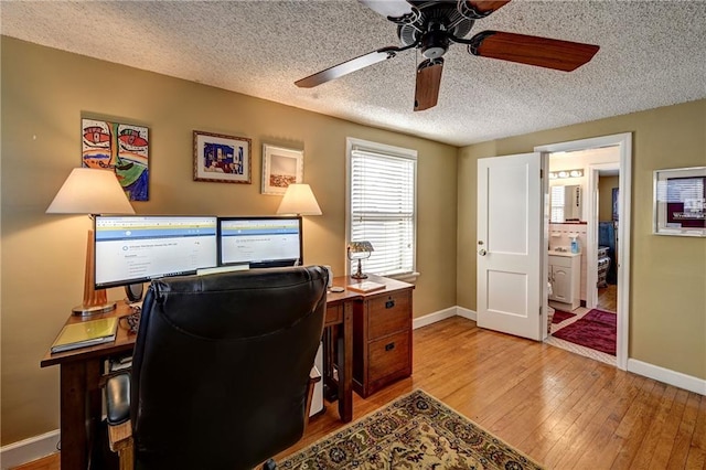 home office with baseboards, wood-type flooring, a textured ceiling, and a ceiling fan