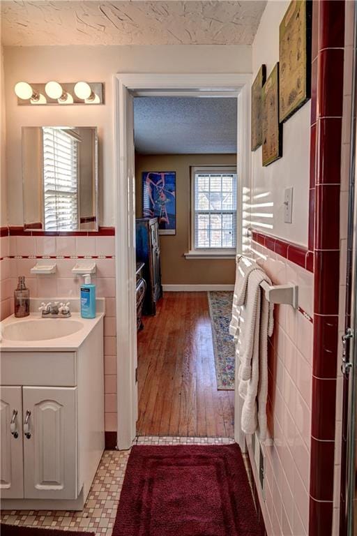 bathroom with a textured ceiling, tile walls, and wainscoting