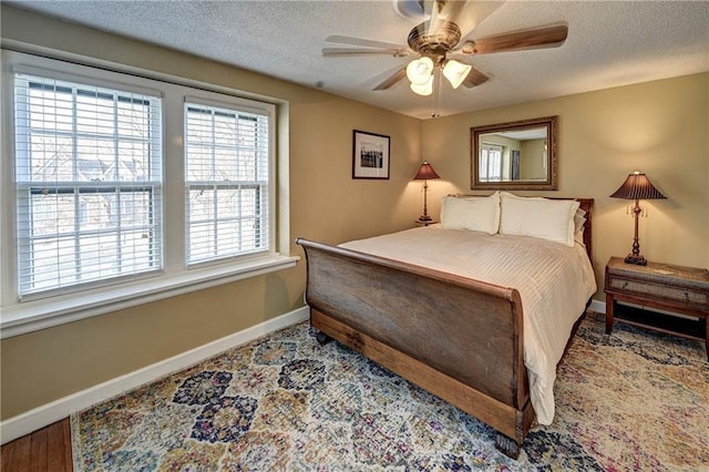 bedroom featuring wood finished floors, a textured ceiling, baseboards, and a ceiling fan