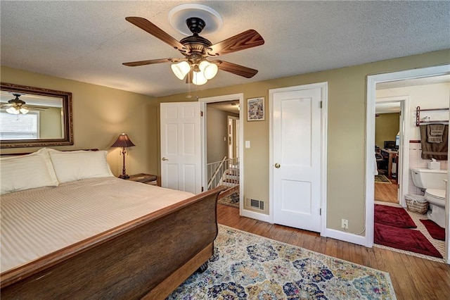 bedroom featuring ceiling fan, wood finished floors, baseboards, and a textured ceiling