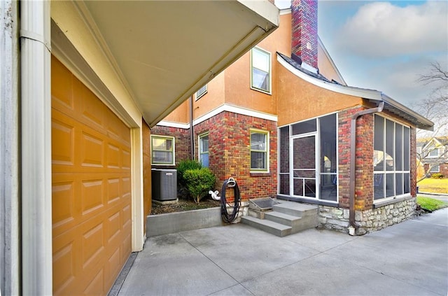 property entrance featuring central air condition unit, brick siding, and a chimney