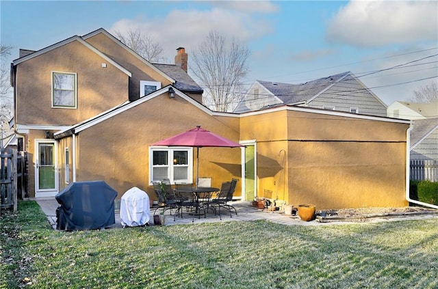 rear view of house featuring a yard, a patio area, fence, and stucco siding