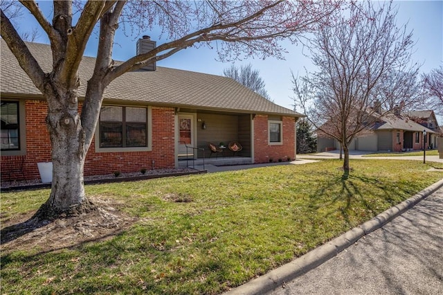 ranch-style home featuring brick siding, a chimney, a front lawn, and a shingled roof