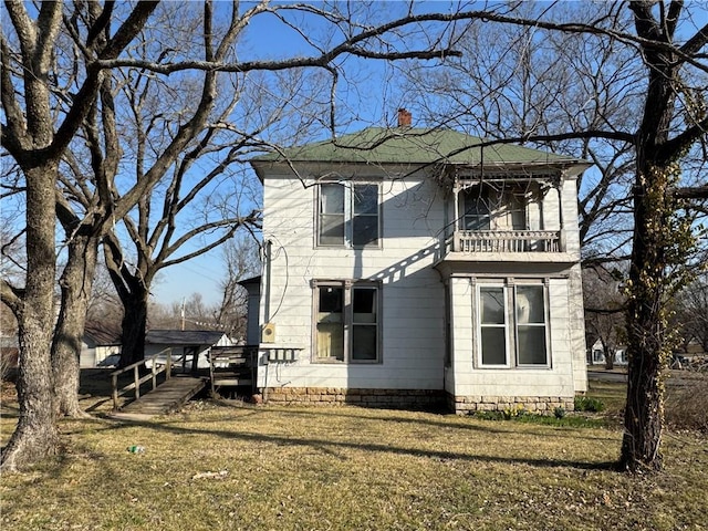 view of side of property with a lawn, a chimney, and a balcony