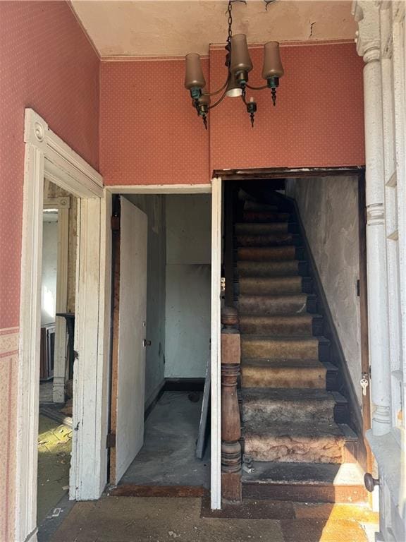 staircase featuring a chandelier and wallpapered walls