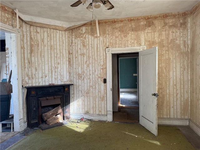 unfurnished living room with ceiling fan and a fireplace