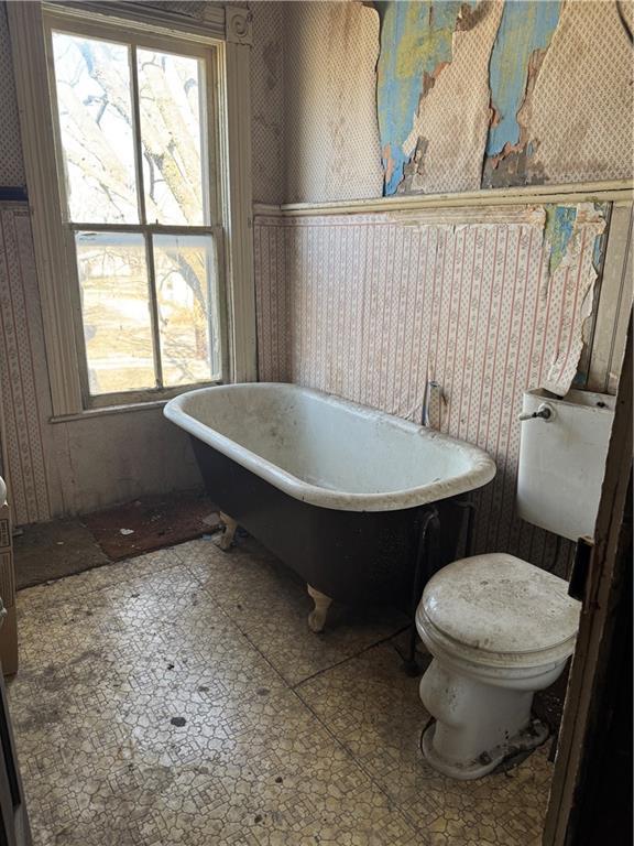 full bathroom featuring toilet, wallpapered walls, and a freestanding tub