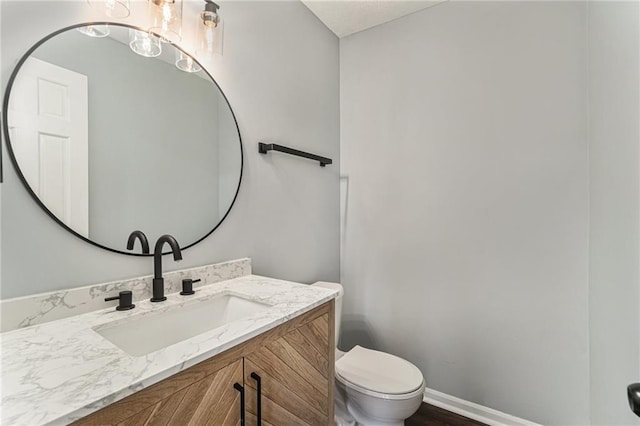 half bath with toilet, vanity, and baseboards