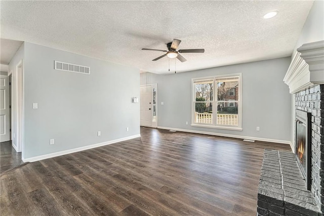 unfurnished living room featuring visible vents, a brick fireplace, dark wood-type flooring, and a ceiling fan