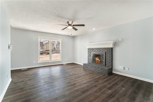 unfurnished living room featuring dark wood-type flooring, a brick fireplace, a ceiling fan, and baseboards