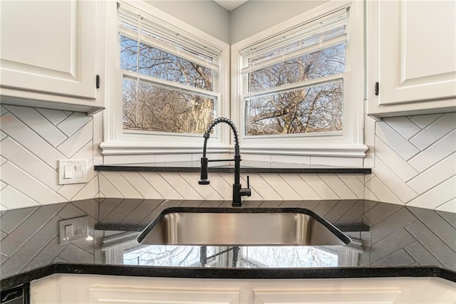 kitchen featuring tasteful backsplash, white cabinetry, and a sink