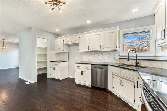 kitchen featuring a sink, dark countertops, dark wood finished floors, dishwasher, and a chandelier