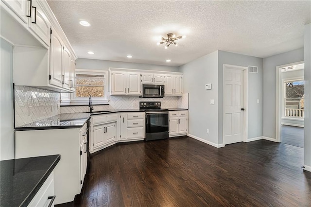 kitchen featuring a sink, stainless steel microwave, dark countertops, dark wood-style floors, and electric range oven