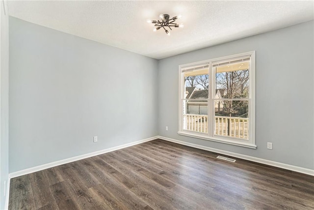 unfurnished room featuring visible vents, baseboards, and dark wood-style flooring