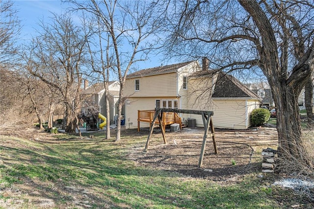 back of house featuring central AC unit, a wooden deck, a yard, a chimney, and a playground