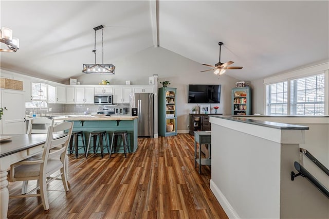 kitchen with a center island, dark wood-type flooring, vaulted ceiling, white cabinets, and stainless steel appliances