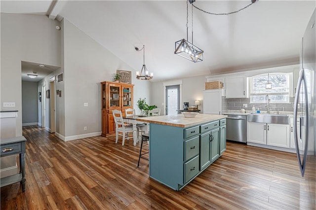 kitchen with a sink, white cabinets, green cabinets, and stainless steel appliances