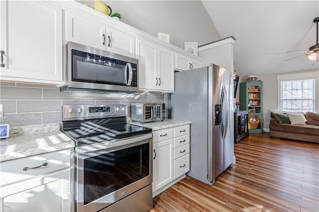 kitchen with open floor plan, stainless steel appliances, white cabinets, ceiling fan, and vaulted ceiling