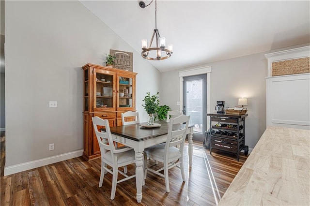 dining room featuring lofted ceiling, a notable chandelier, dark wood-style floors, and baseboards