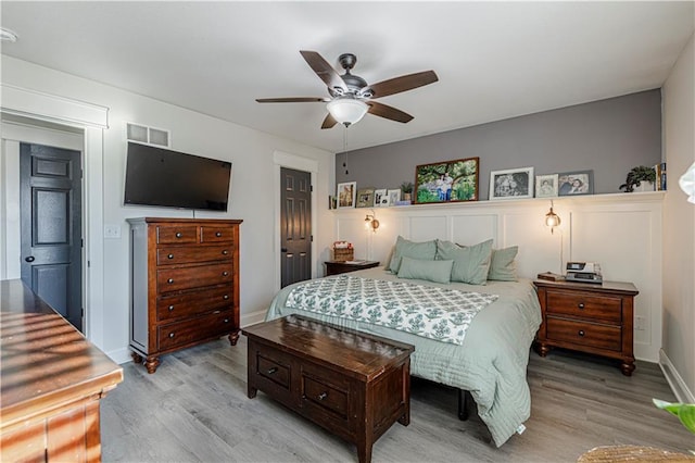 bedroom featuring a ceiling fan, visible vents, light wood finished floors, and baseboards