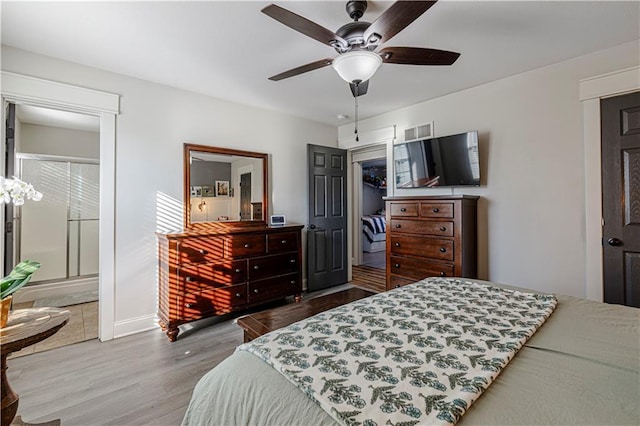 bedroom featuring a ceiling fan, wood finished floors, visible vents, a closet, and connected bathroom