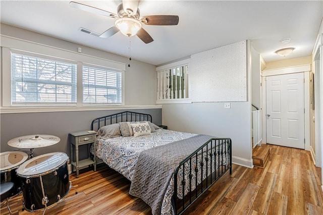 bedroom featuring visible vents, baseboards, wood finished floors, and a ceiling fan