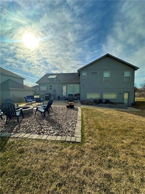 rear view of property with a yard, a fire pit, and a patio area