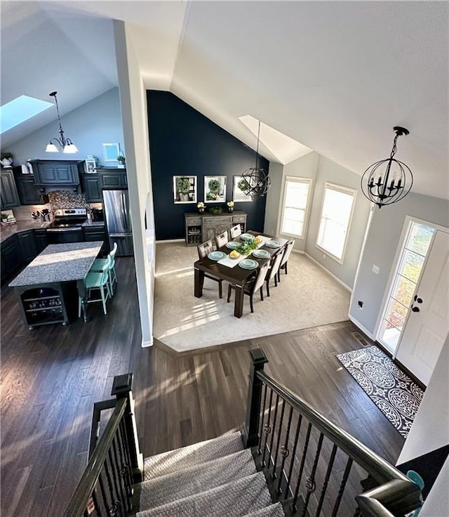 entrance foyer with dark wood-style floors, lofted ceiling, and an inviting chandelier