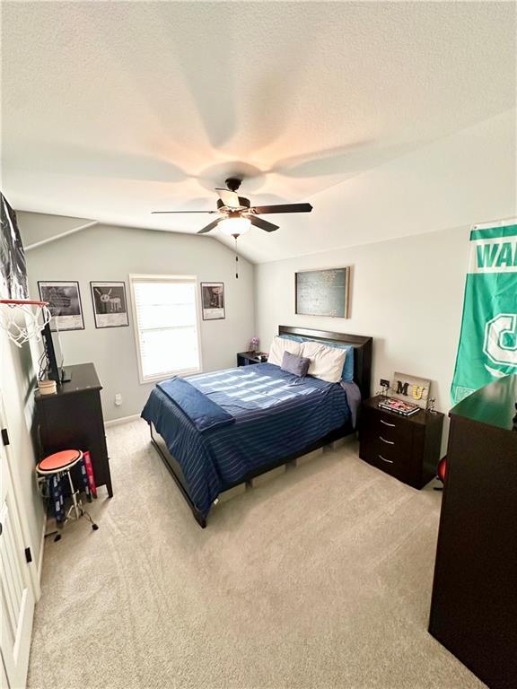 bedroom featuring carpet flooring, a textured ceiling, a ceiling fan, and vaulted ceiling