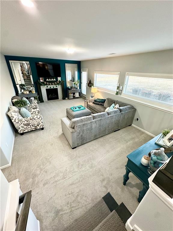 carpeted living room featuring a fireplace and baseboards