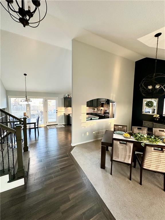 dining space with dark wood finished floors, a notable chandelier, high vaulted ceiling, and baseboards