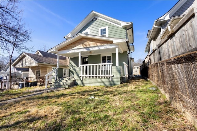 view of front of property featuring a porch, a front yard, and fence