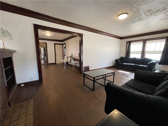 living room with dark wood-type flooring, crown molding, visible vents, and baseboards