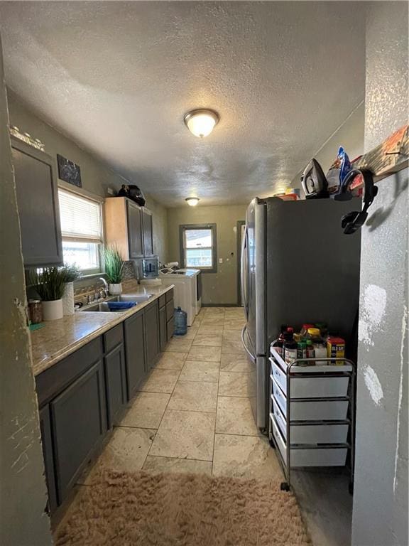 kitchen featuring a wealth of natural light, a textured ceiling, light countertops, and a sink