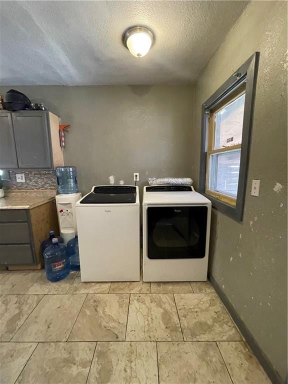 laundry area featuring baseboards, a textured ceiling, and washing machine and dryer