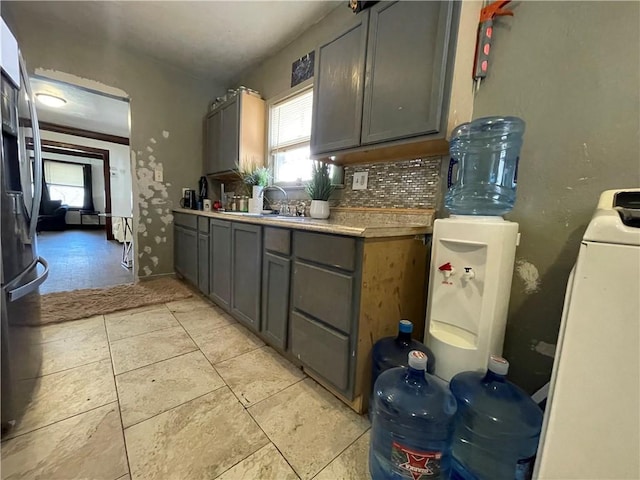 kitchen featuring a wealth of natural light, a sink, gray cabinets, and stainless steel fridge with ice dispenser