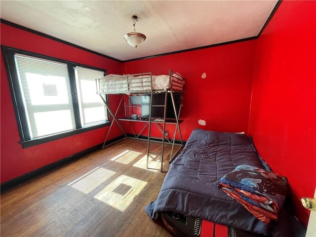 bedroom featuring crown molding, baseboards, and wood finished floors