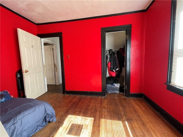 bedroom with ornamental molding, baseboards, and wood finished floors