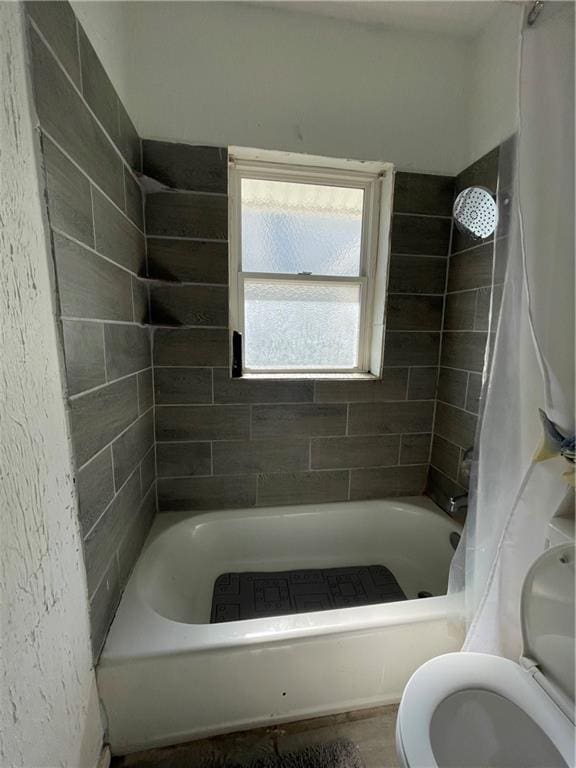 bathroom featuring toilet and shower / tub combo with curtain