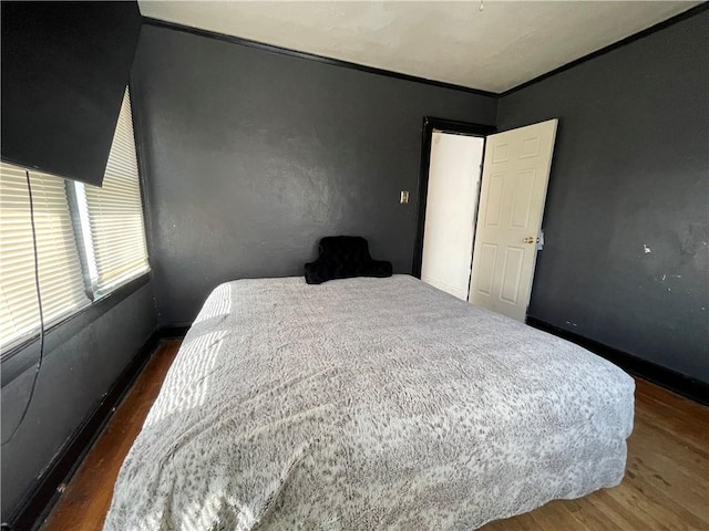 bedroom featuring crown molding and wood finished floors