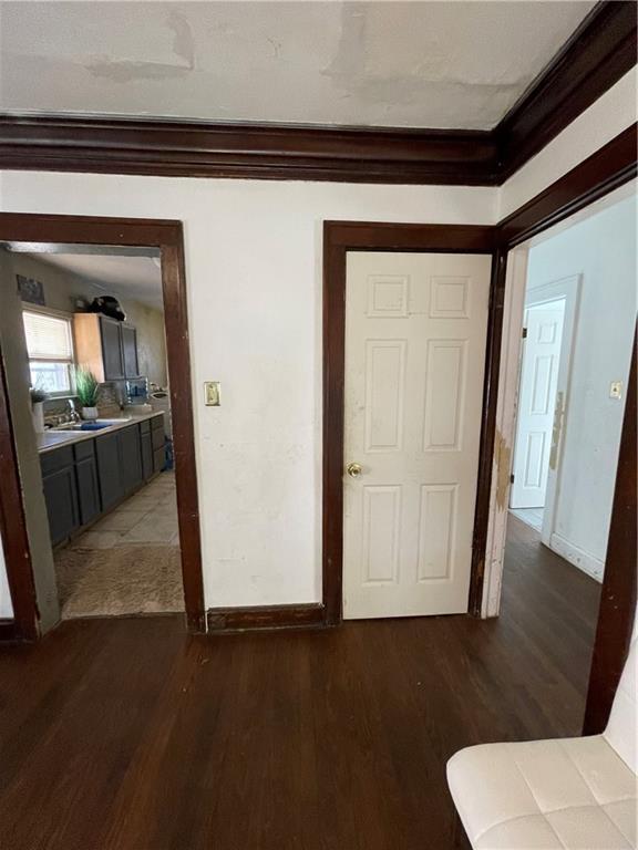 bedroom with a sink, baseboards, wood finished floors, and crown molding