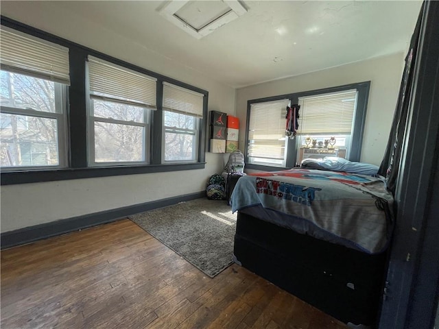 bedroom featuring attic access, baseboards, and hardwood / wood-style floors