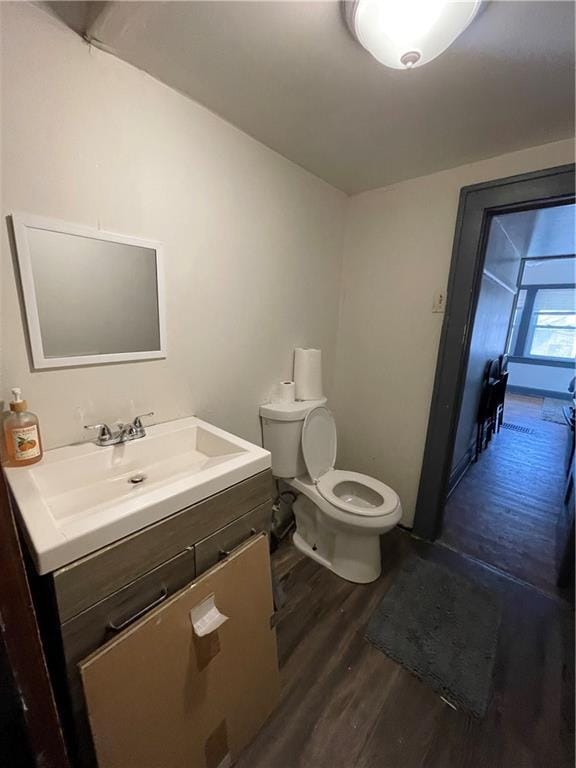 half bathroom featuring toilet, wood finished floors, and vanity