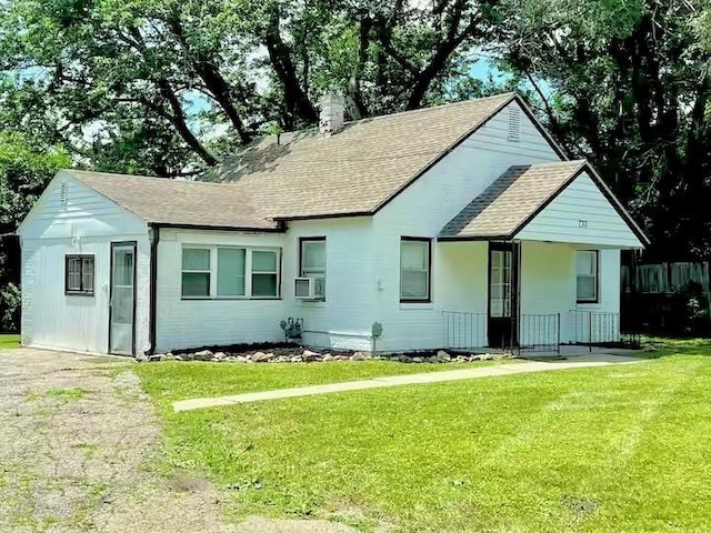 view of front of property with cooling unit, roof with shingles, a chimney, and a front yard