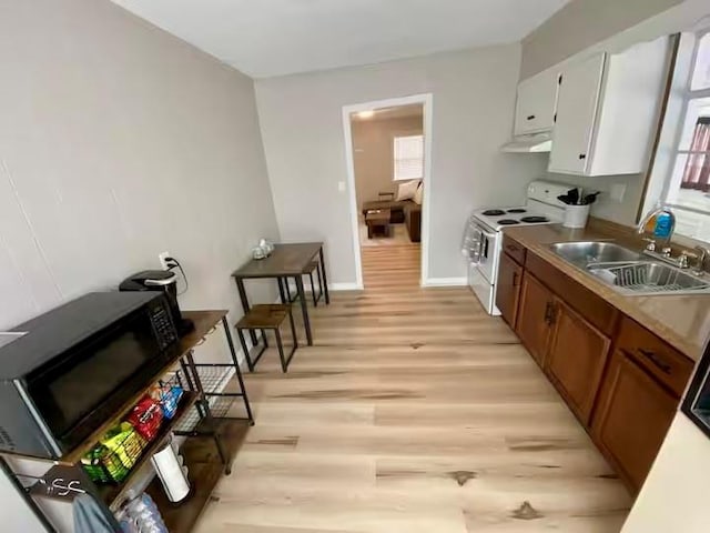 kitchen featuring a sink, under cabinet range hood, white electric range oven, light wood-style floors, and black microwave