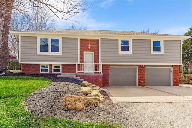 raised ranch featuring brick siding, concrete driveway, a garage, and a front yard