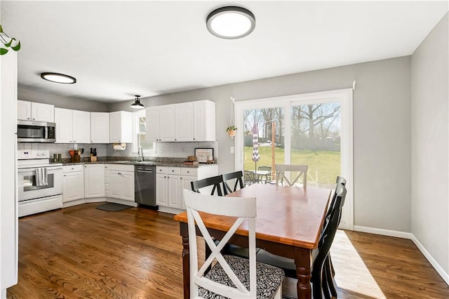 kitchen with a sink, tasteful backsplash, dark wood-type flooring, and appliances with stainless steel finishes