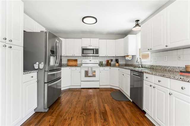 kitchen with tasteful backsplash, stone counters, stainless steel appliances, white cabinetry, and a sink