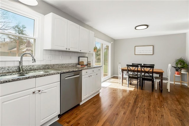 kitchen with a sink, light stone counters, backsplash, dark wood finished floors, and dishwasher