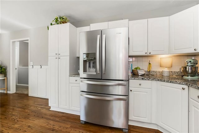 kitchen featuring dark stone counters, decorative backsplash, white cabinets, and stainless steel fridge with ice dispenser